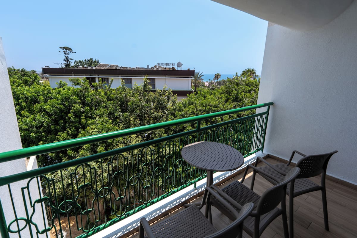 A balcony with a green railing, a round table, and two chairs.