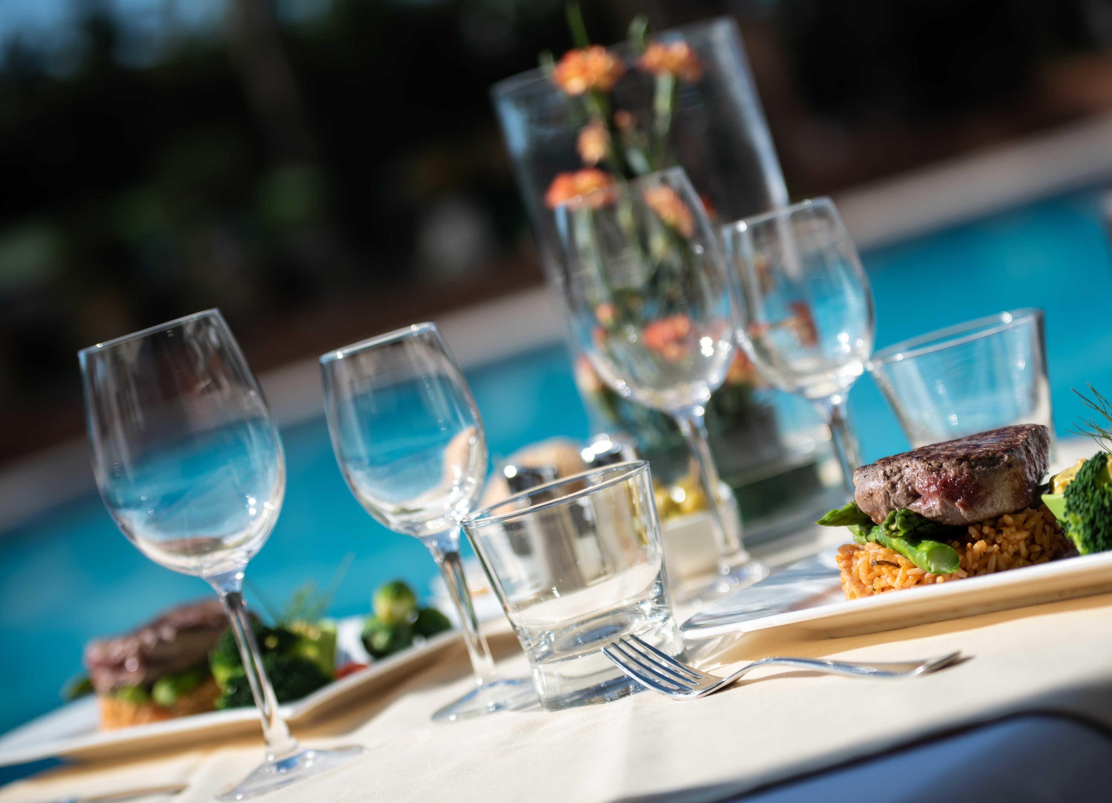 Una mesa de comedor con varias copas de vino, un tenedor y un plato con comida.