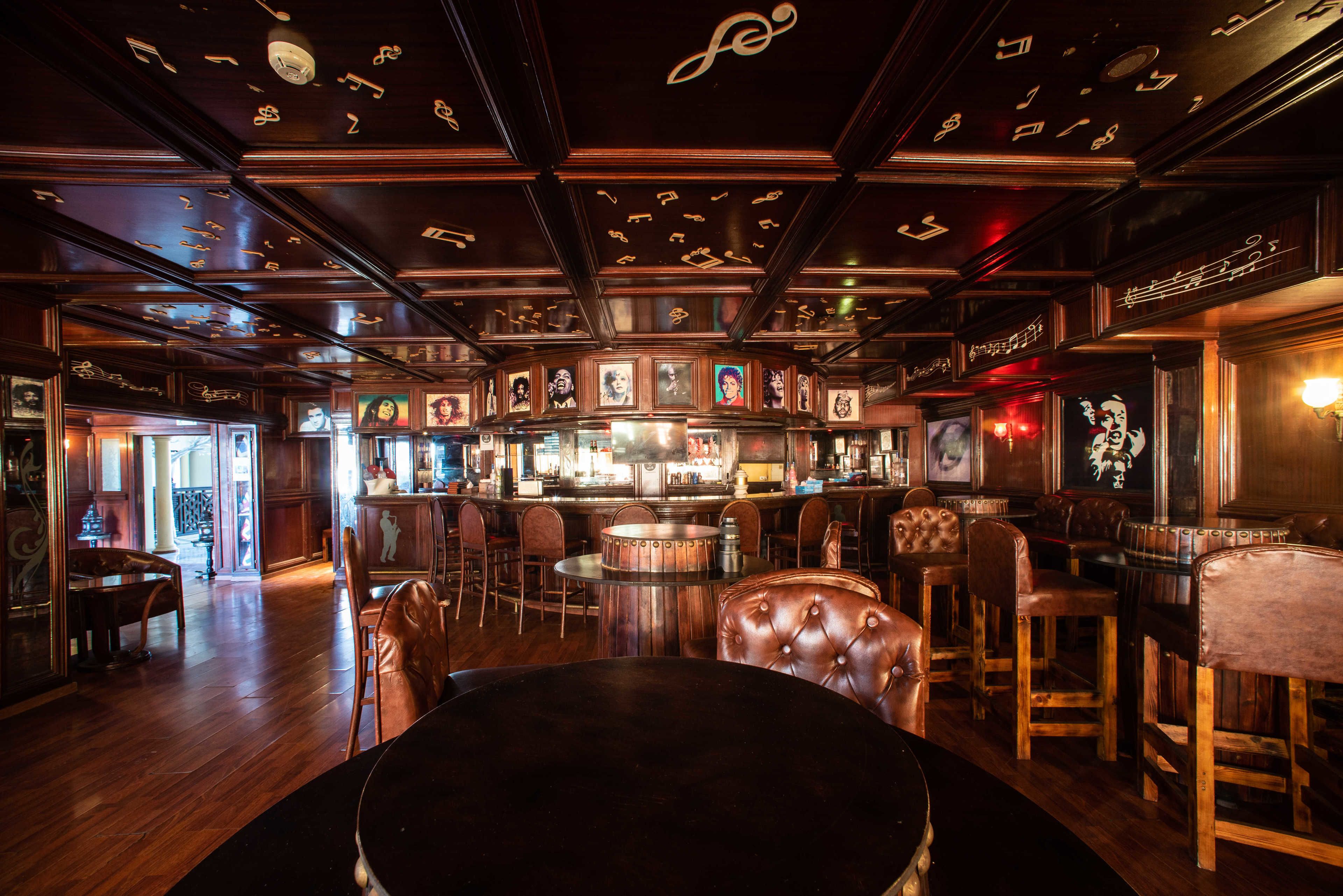 A bar with wooden furniture and a ceiling decorated with musical notes.