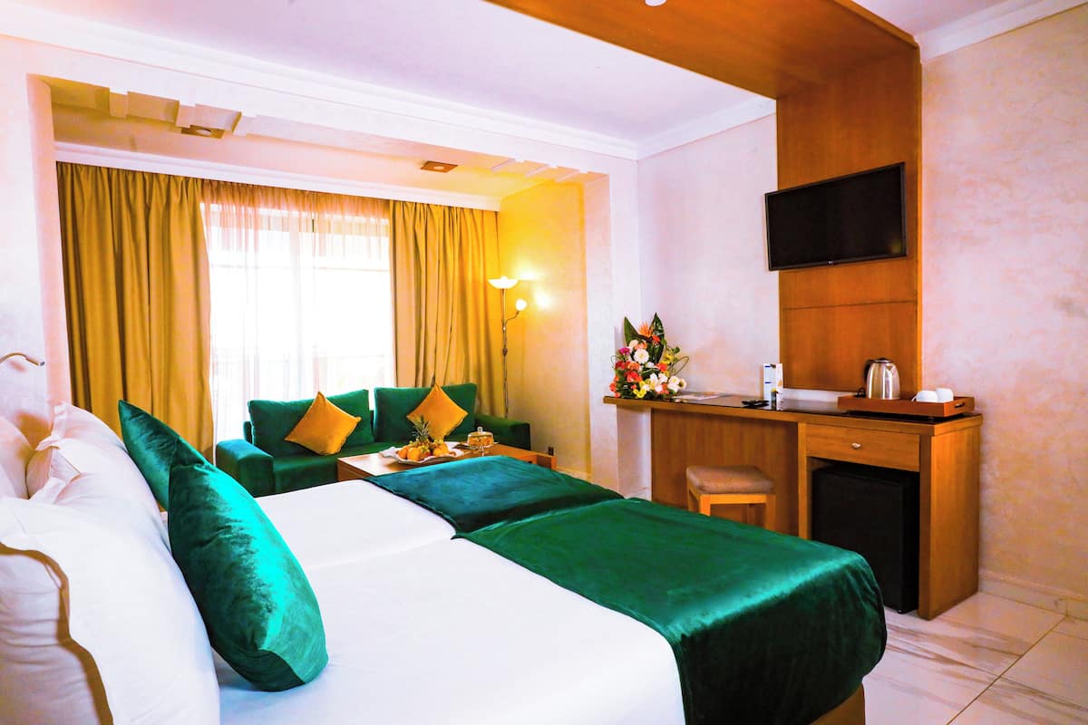 A hotel room with a bed, a desk, a TV, and a small kitchenette.