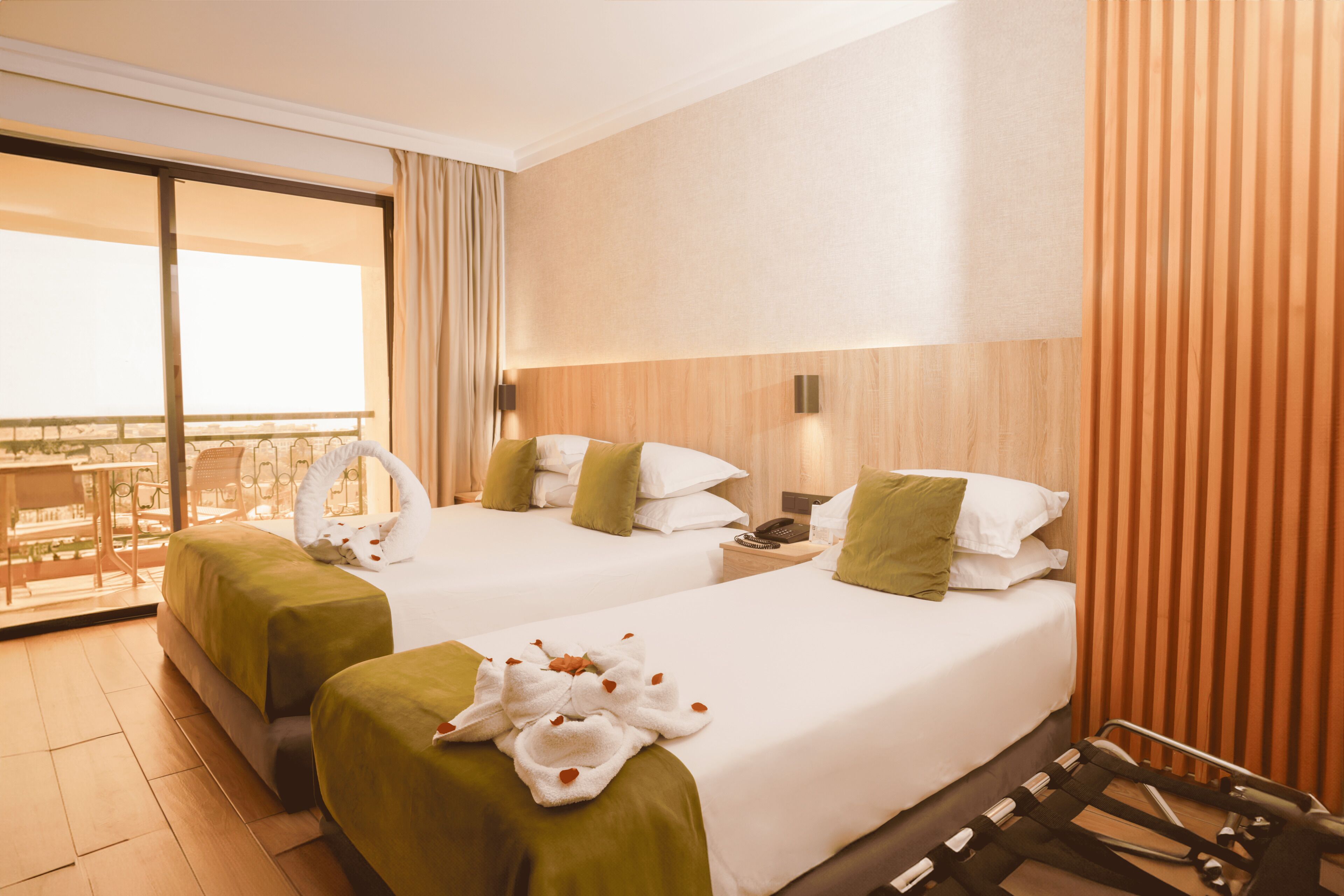 A hotel room with two beds, a balcony, and a view of the city.