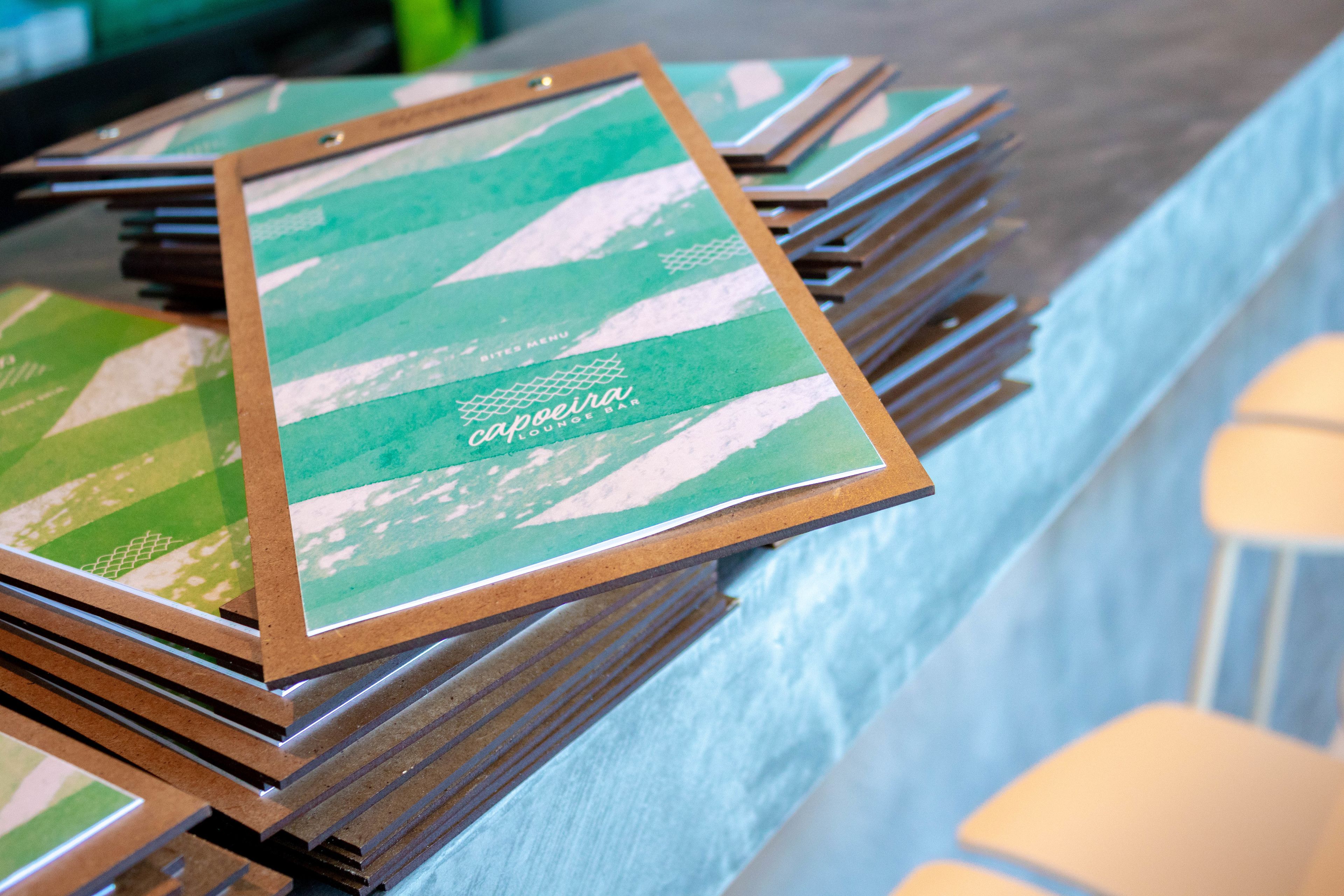A stack of menu cards with a green and white design, placed on a counter.