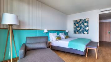 A hotel room with a bed, a sofa, a floor lamp, and a painting on the wall.