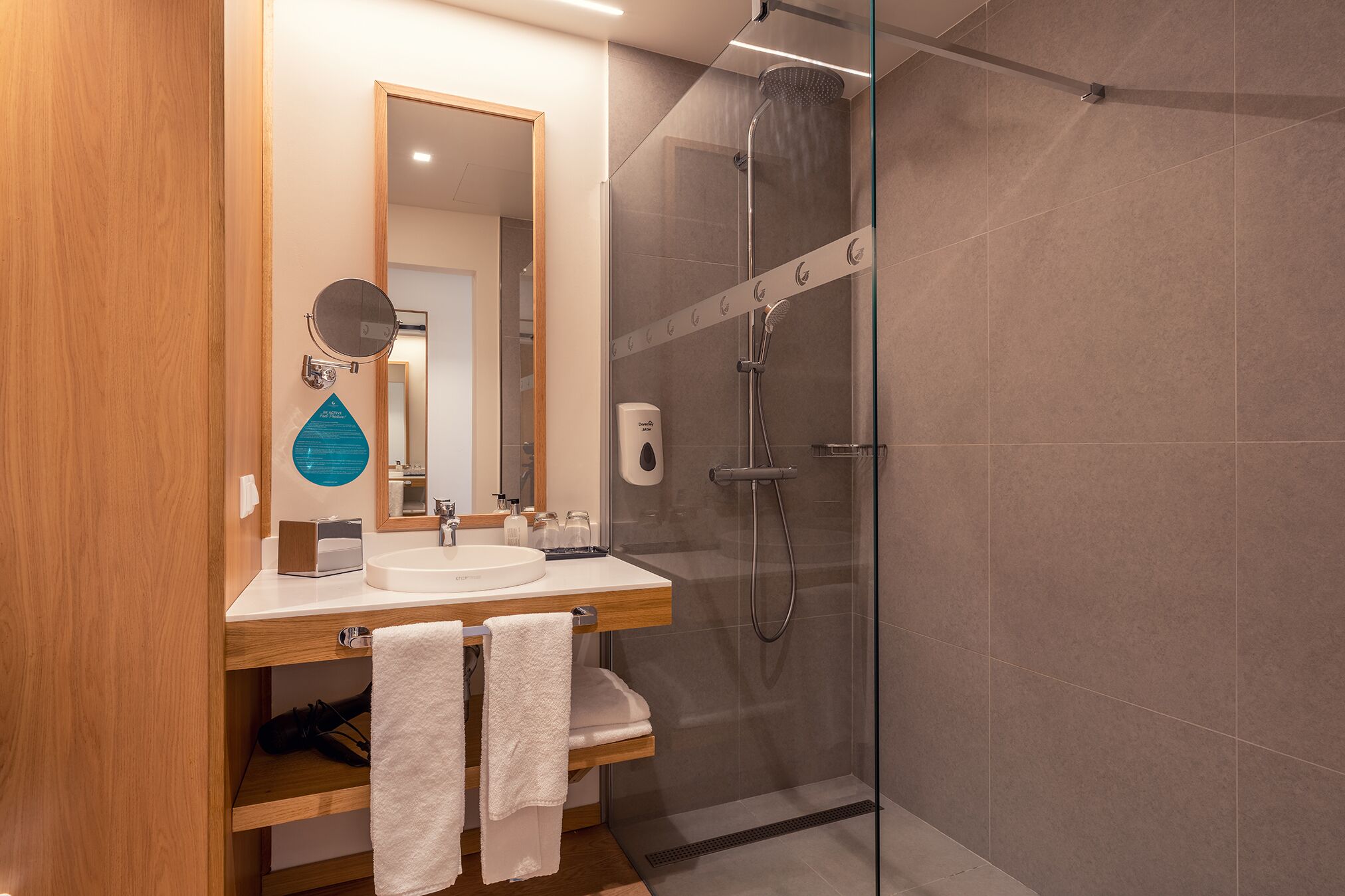 A modern bathroom with a glass-enclosed shower, a wooden vanity with a sink, and a mirror.