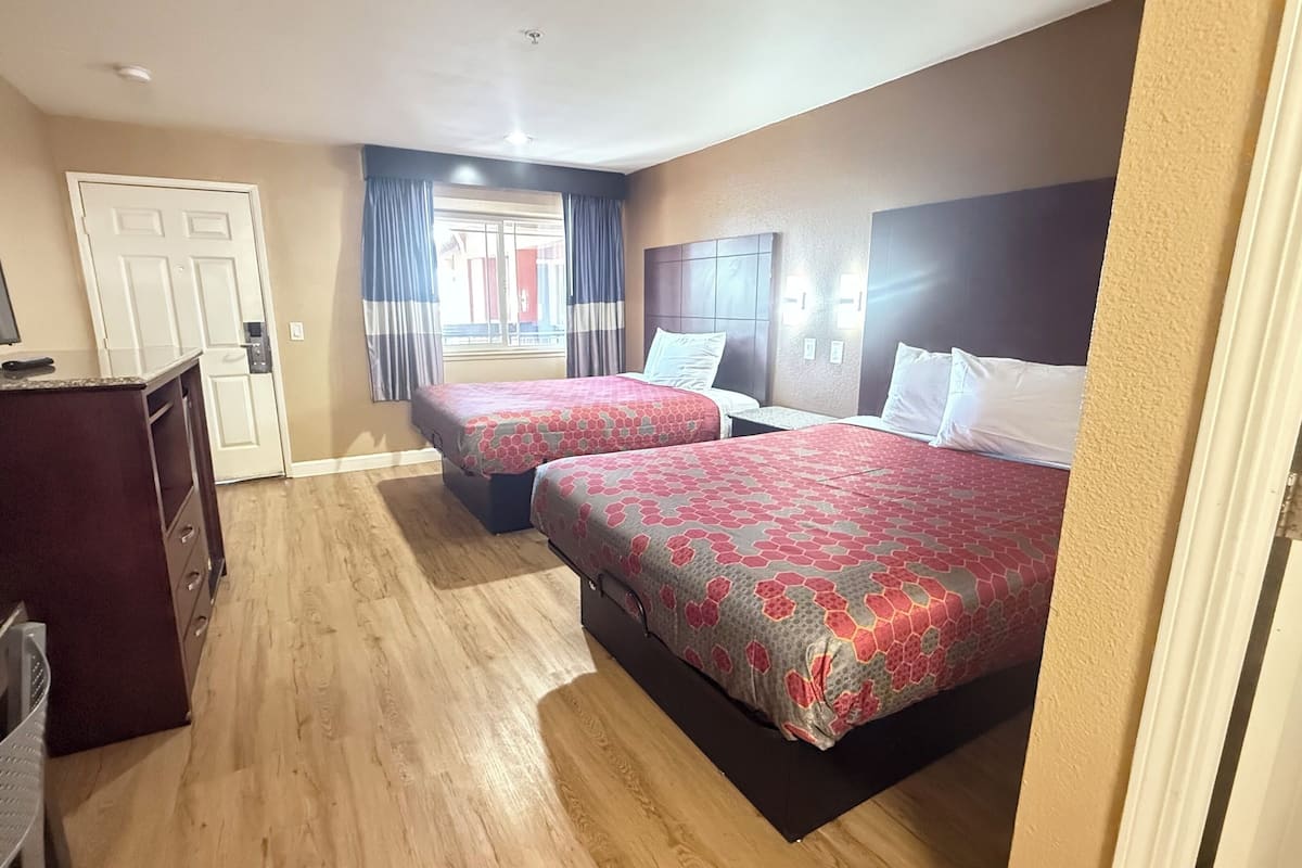 A hotel room with two beds, a desk, and a television.