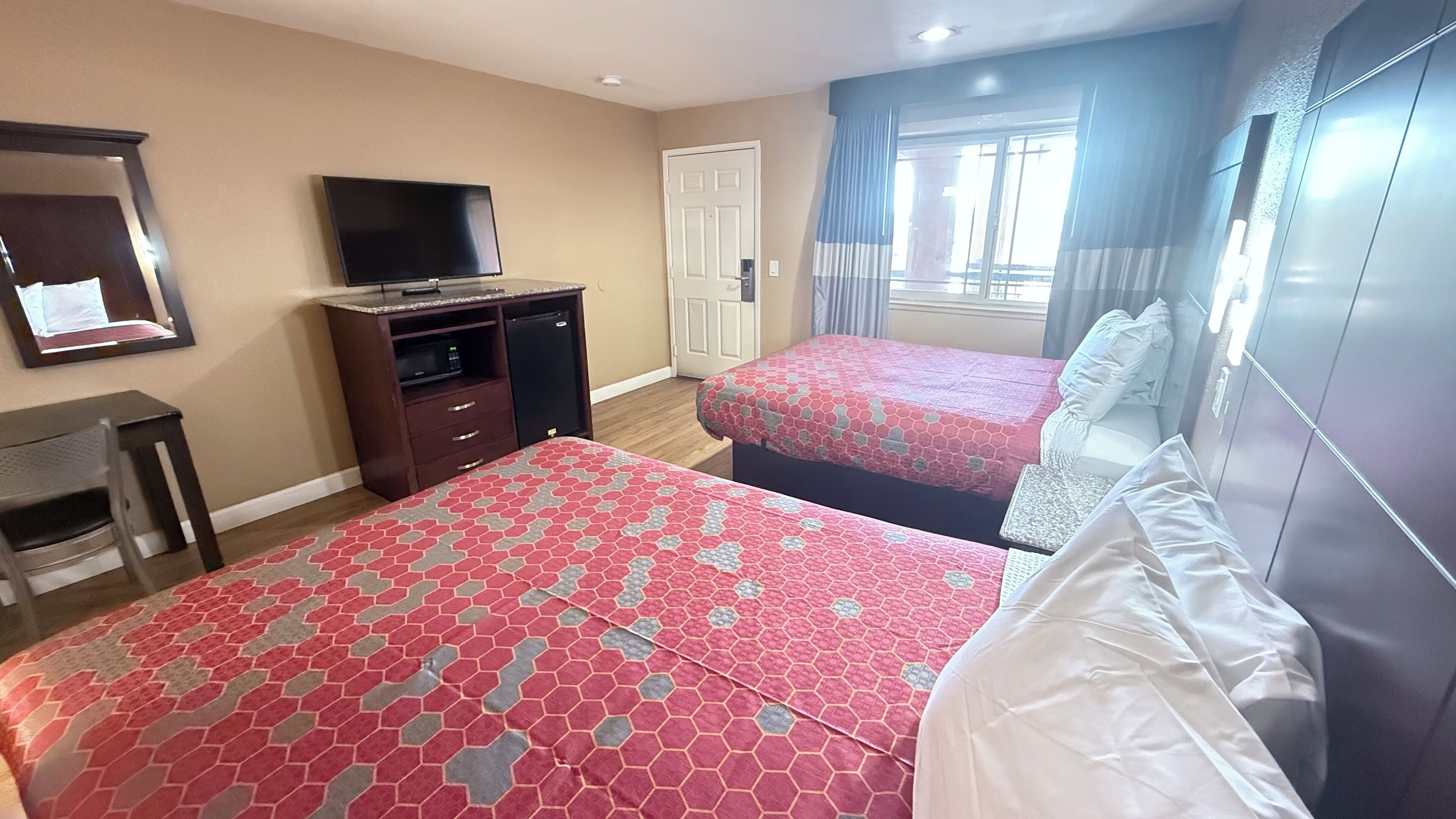 Een hotelkamer met twee bedden, een televisie, een bureau en een garderobe.