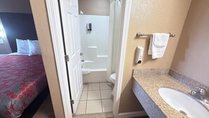 A hotel bathroom with a shower, toilet, and sink. - Valley Inn (Watsonville)