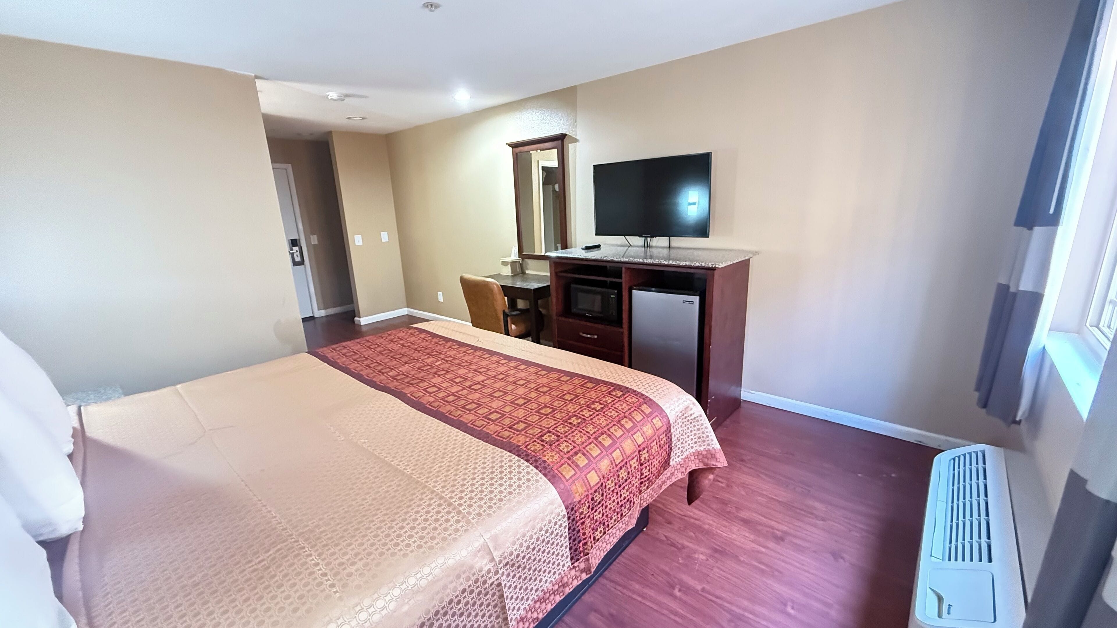 Une chambre d’hôtel avec un lit, un bureau, une télévision et une fenêtre.