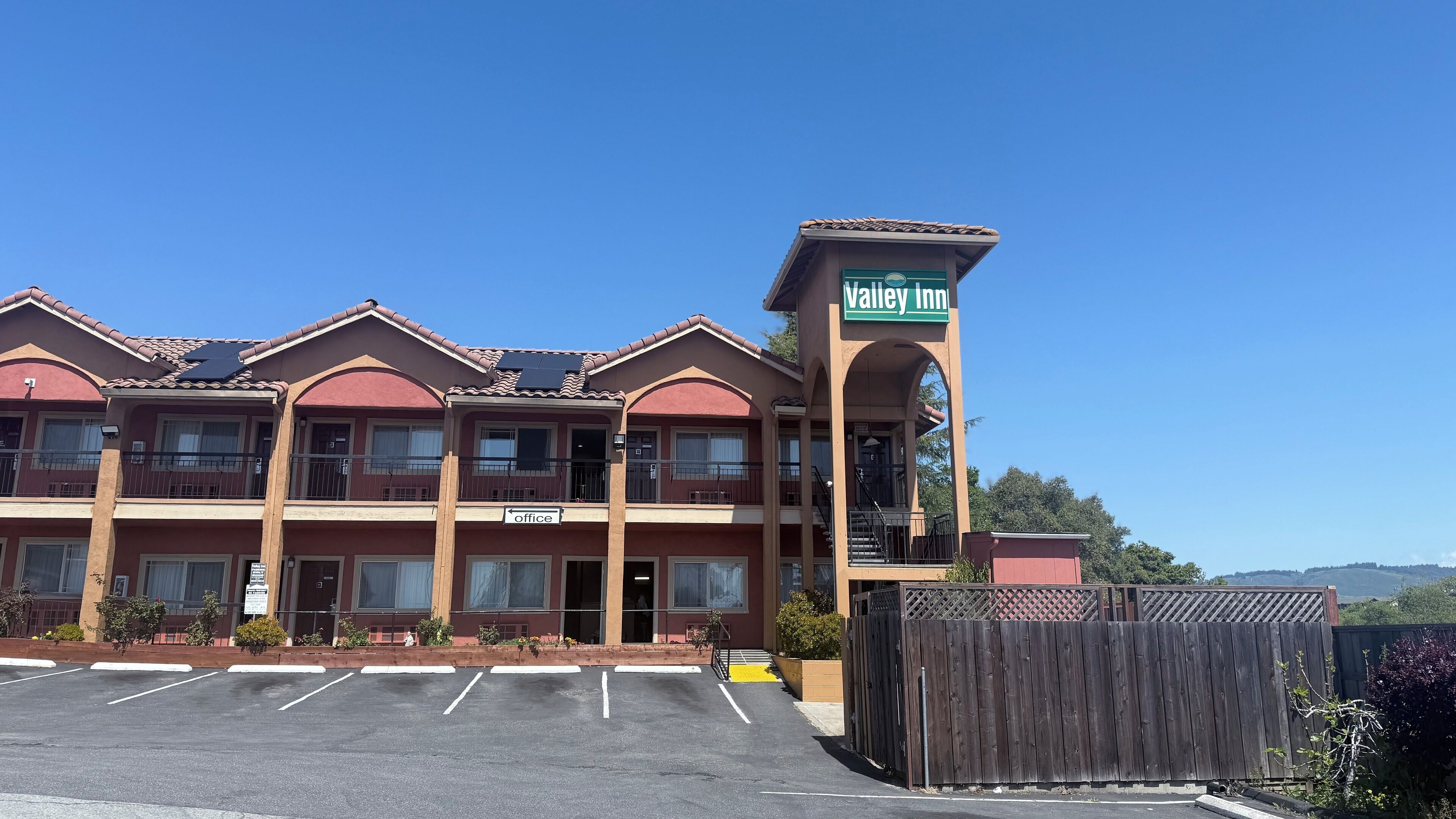 Un hotel a più piani con un evidente cartello 'Valley Inn', numerosi balconi e un parcheggio di fronte.