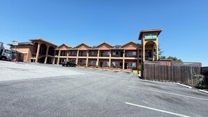 A multi-story hotel with a central courtyard, a parking lot, and a fenced area. - Valley Inn (Watsonville)