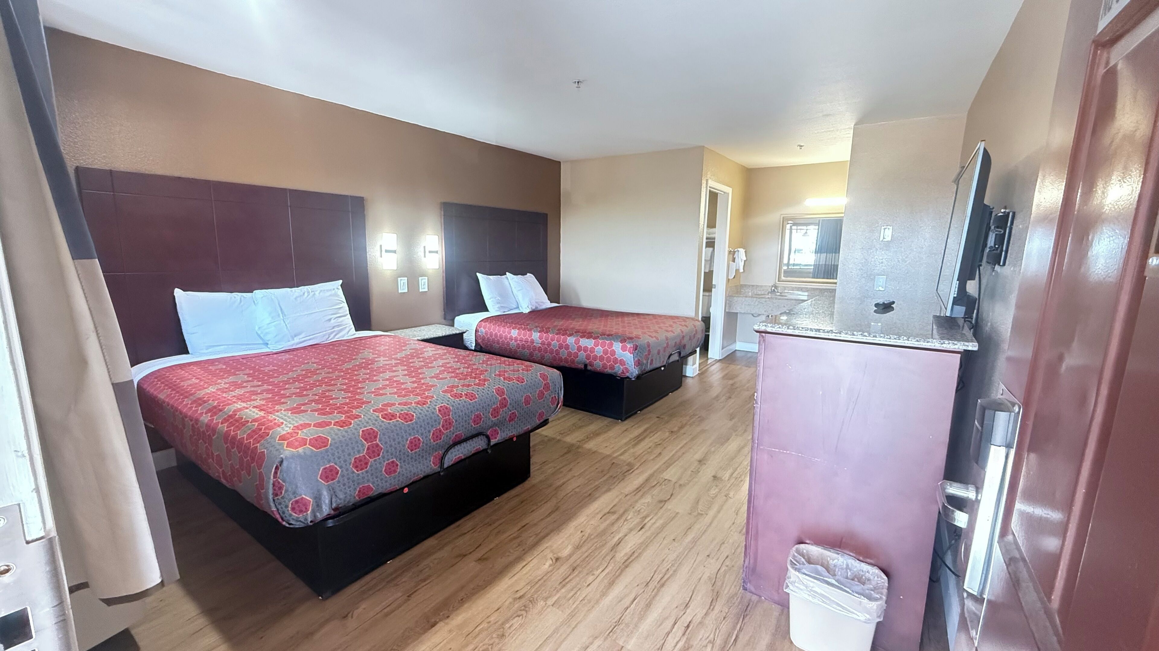 Habitación de hotel con dos camas, kitchenette y baño.