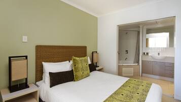 A hotel room with a bed, nightstands, a mirror, and a bathroom visible through an open door.