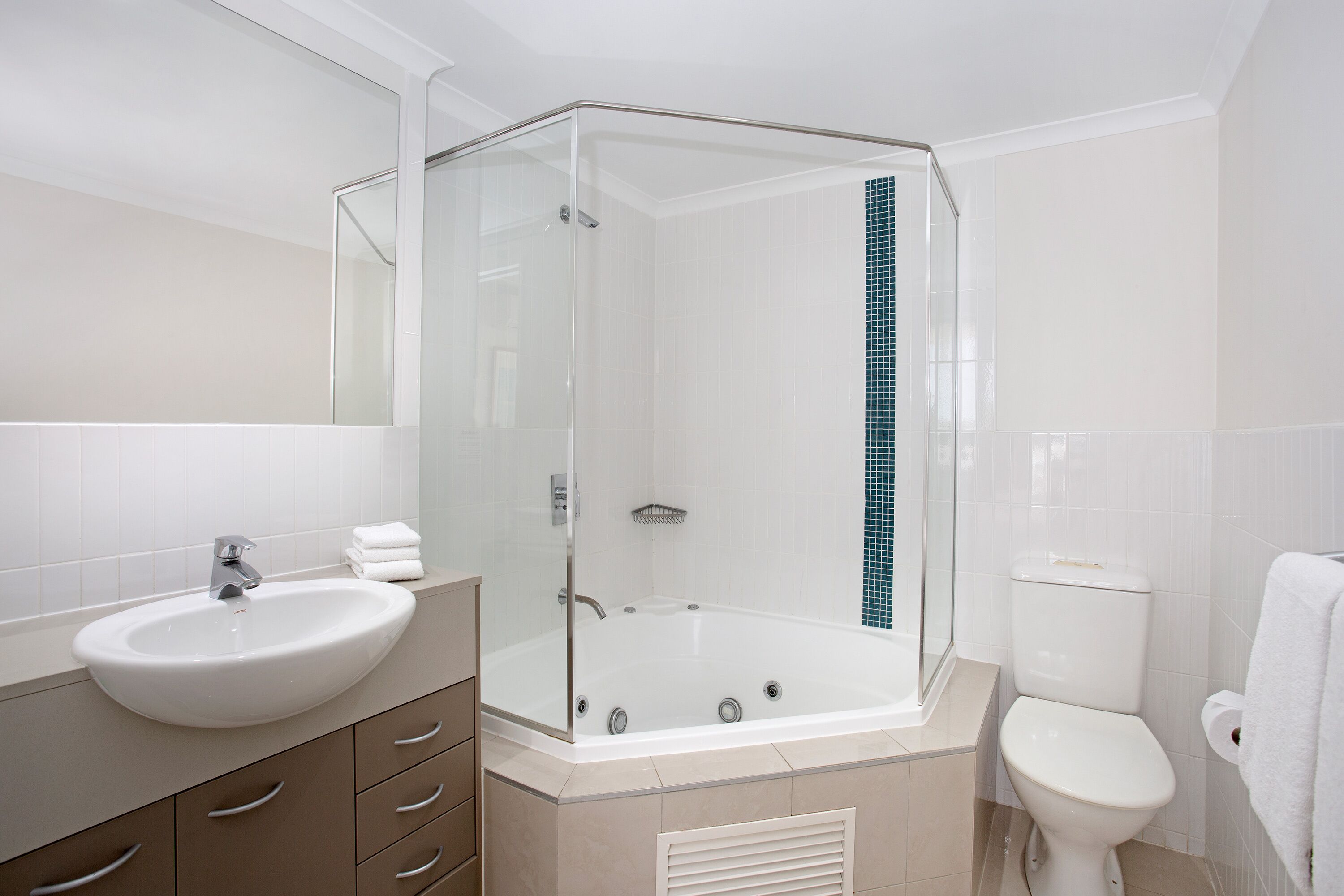 A modern bathroom with a glass-enclosed shower, a white sink, and a toilet.