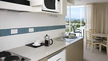A modern kitchen with a microwave, coffee maker, and sink. There is a dining area with a table and chairs.