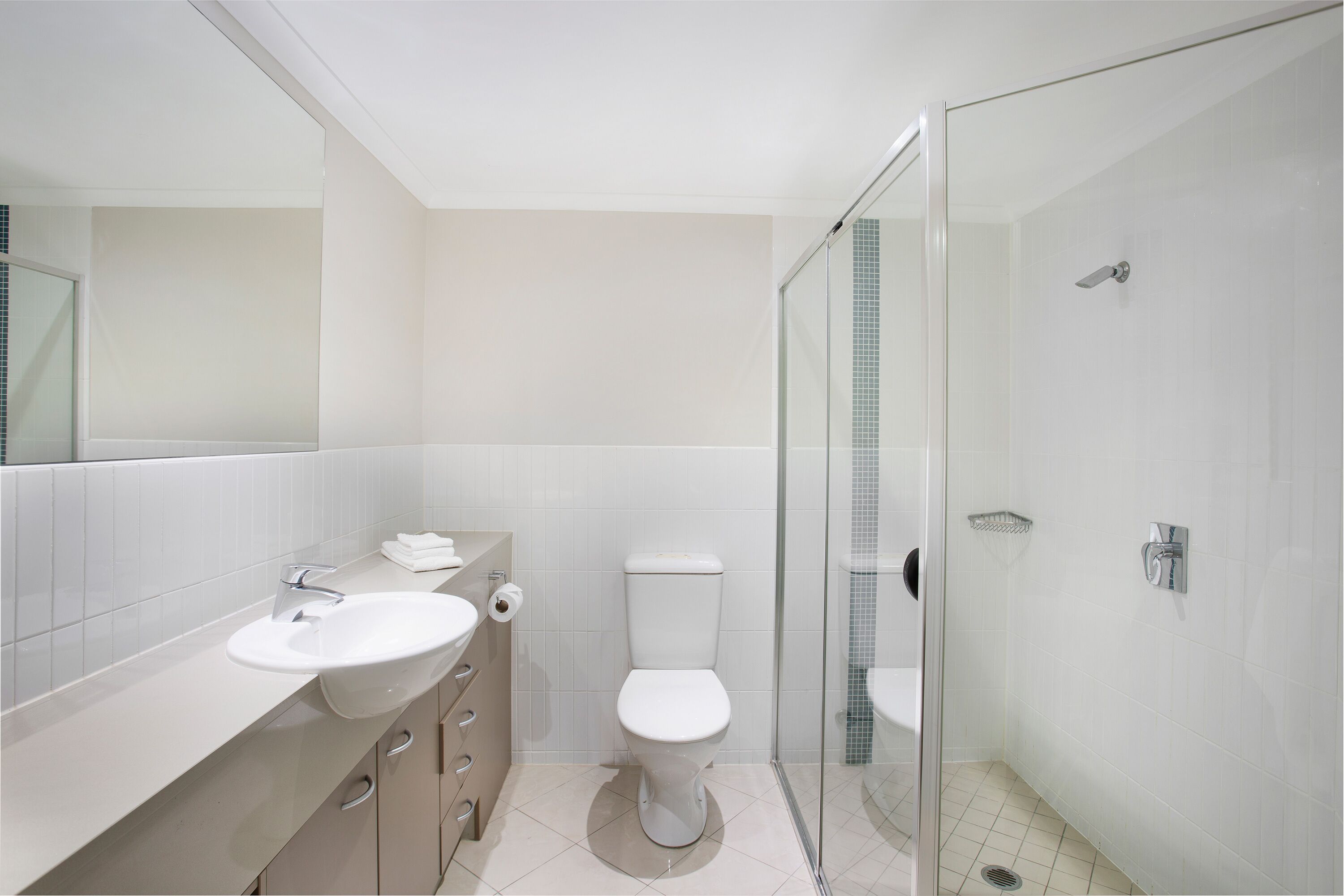 A modern bathroom with a glass-enclosed shower, a white sink, and a toilet.