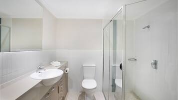 A modern bathroom with a glass-enclosed shower, a white sink, and a toilet.