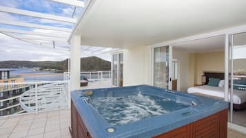 Un balcon avec un jacuzzi, un lit et une vue sur la mer.