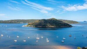 Una zona costera con una pequeña isla rodeada de aguas tranquilas. Varias embarcaciones están ancladas cerca de la orilla.