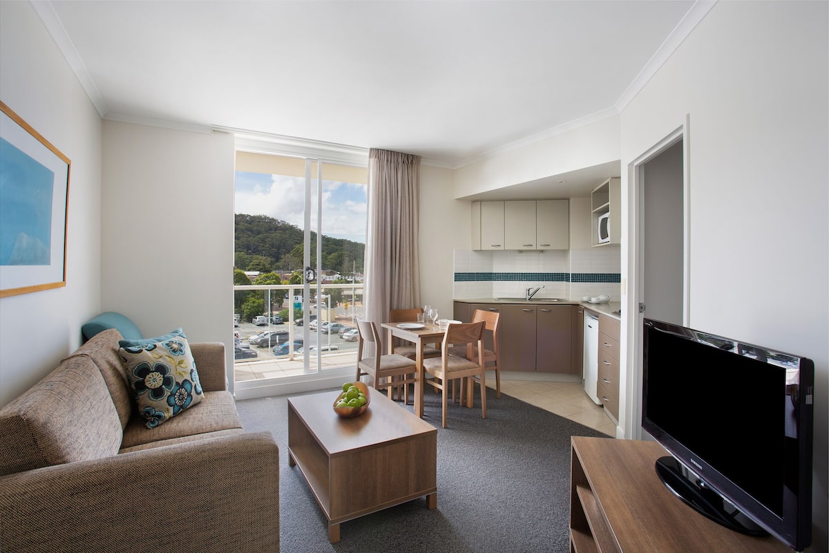 Une chambre d’hôtel moderne dotée d’un balcon, d’un coin repas, d’une télévision et d’une kitchenette.