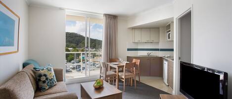 Une chambre d’hôtel moderne dotée d’un espace salon, d’un coin repas et d’une kitchenette.