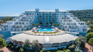 Un hotel de varios pisos con piscina central, asientos exteriores y un área cubierta.