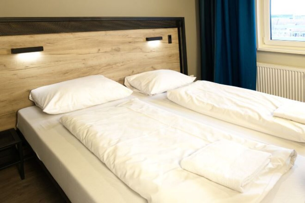 A double bed with white bedding in a hotel room.
