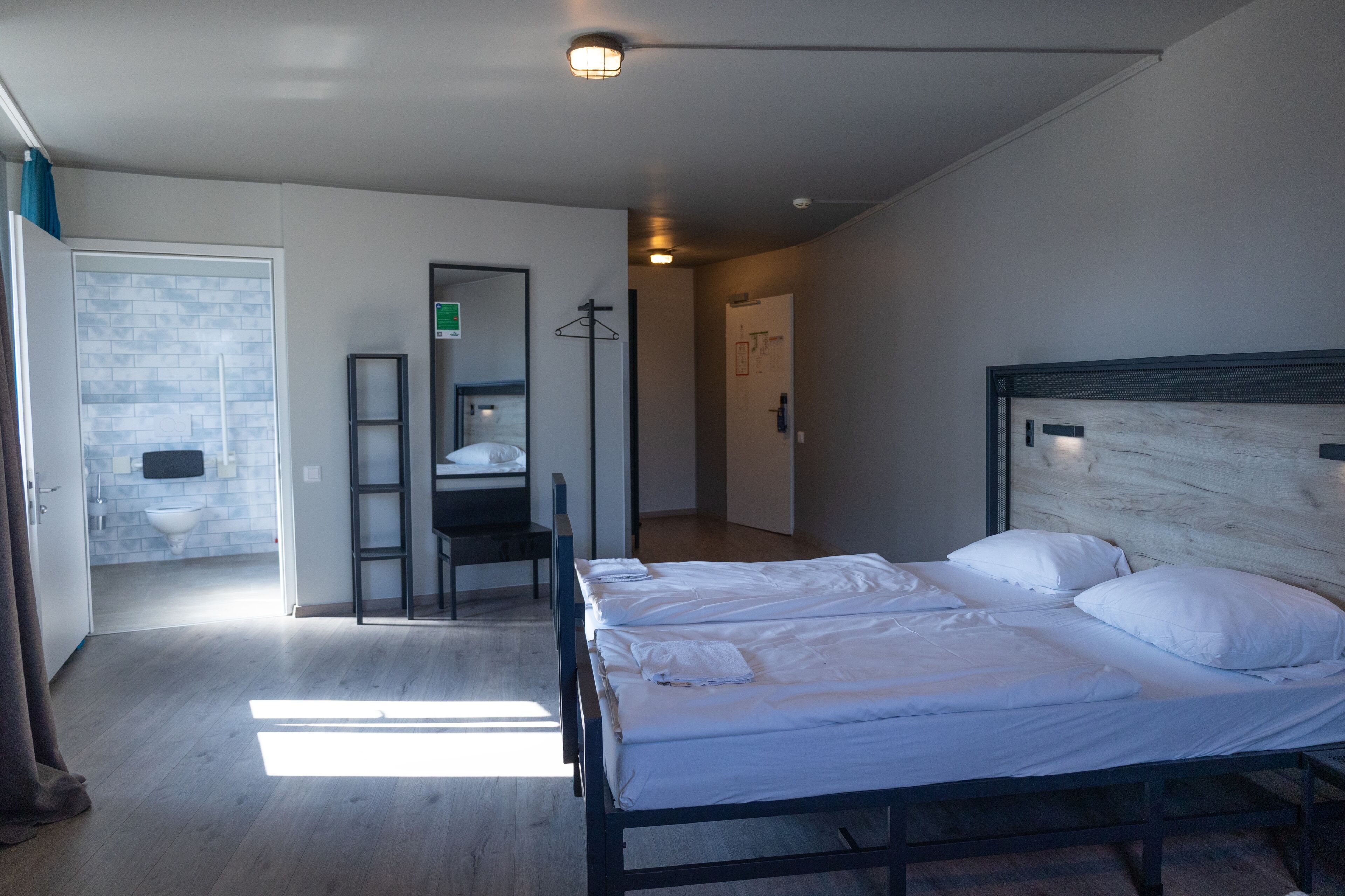 Una habitación de hotel con cama, escritorio y baño visible a través de una puerta abierta.