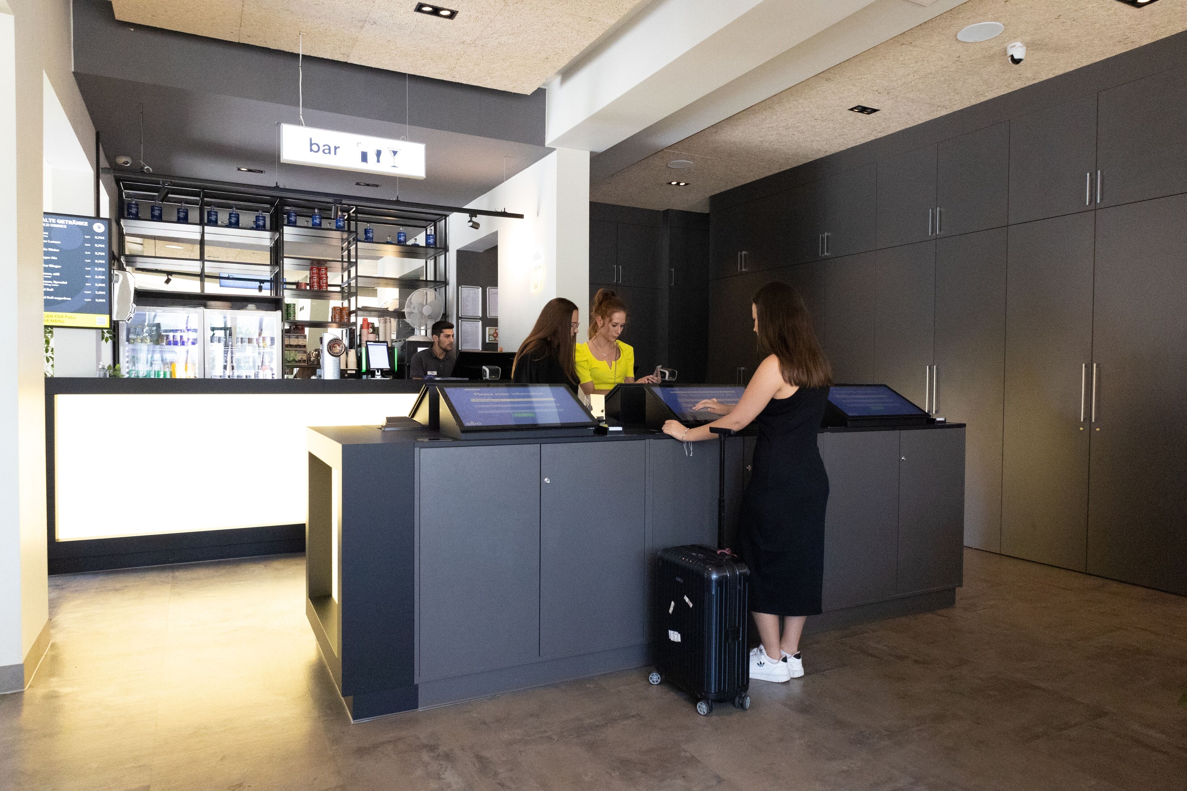 A reception area with a counter, a digital screen, and a bar sign.