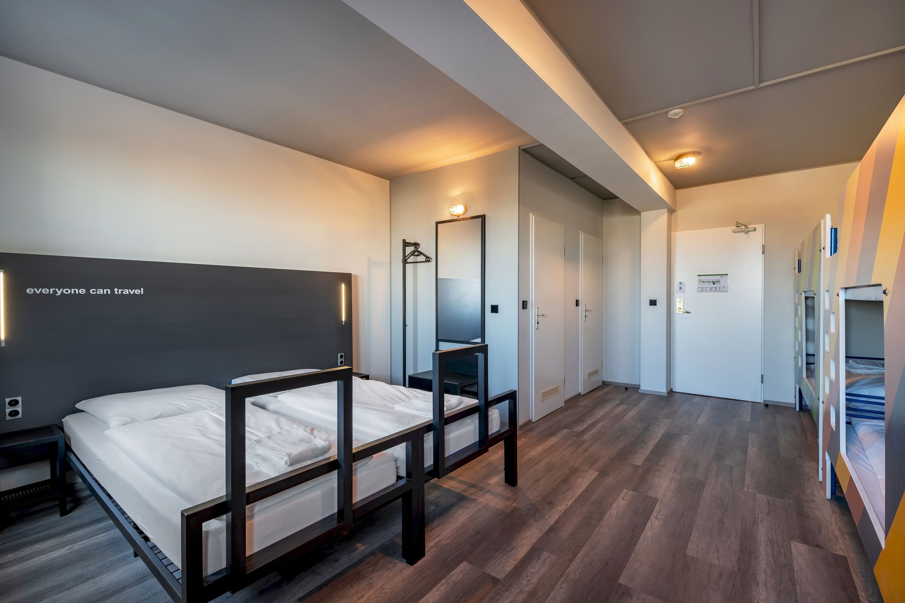 Een moderne hotelkamer met een groot bed, nachtkastjes, een kledingkast en een spiegel.