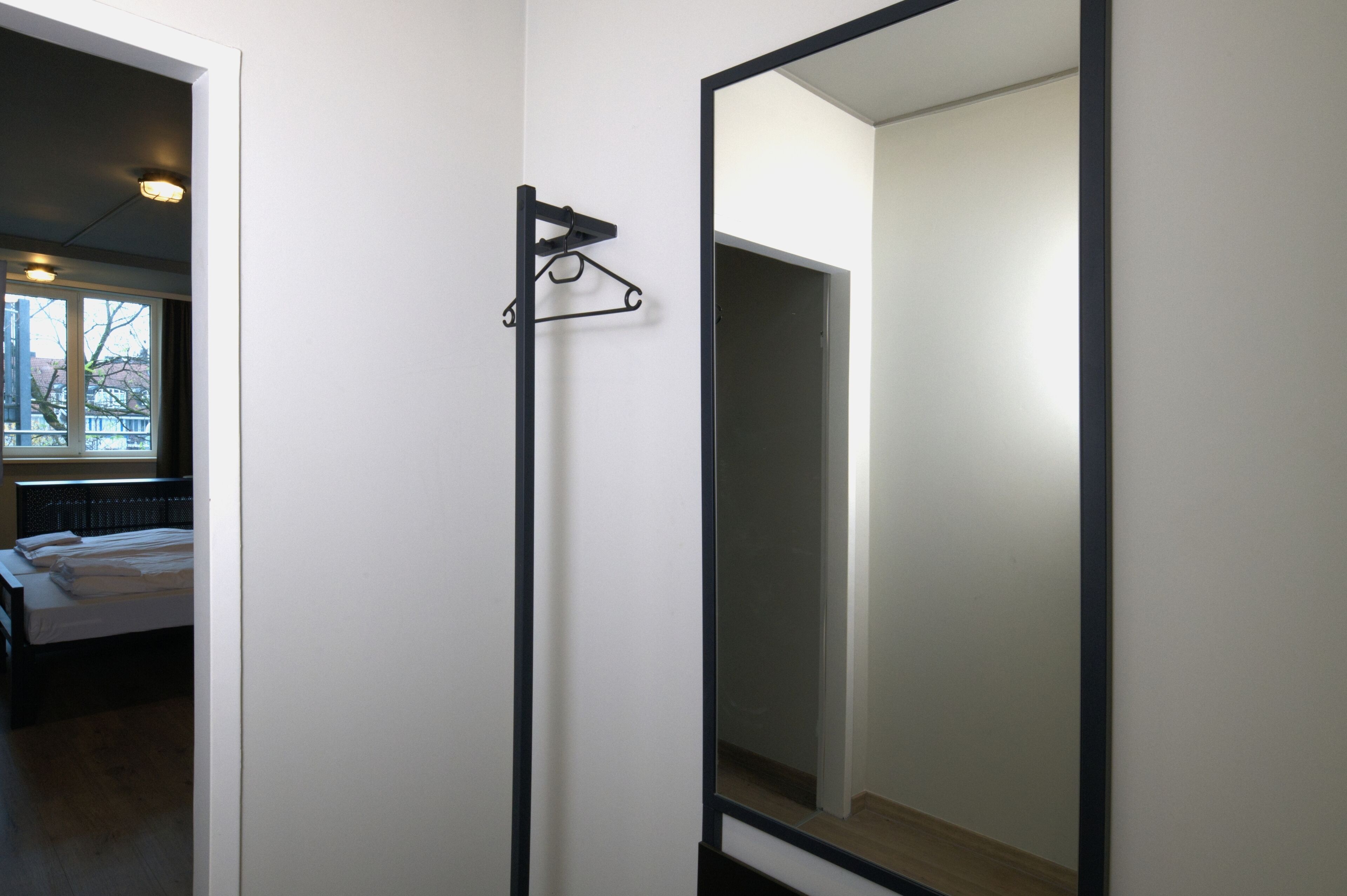 A room with a bed, a hanging light fixture, and a large mirror.