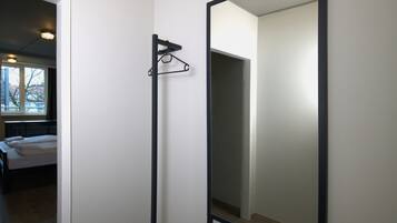 Ein Zimmer mit einem Bett, einer Hängelampe und einem großen Spiegel.