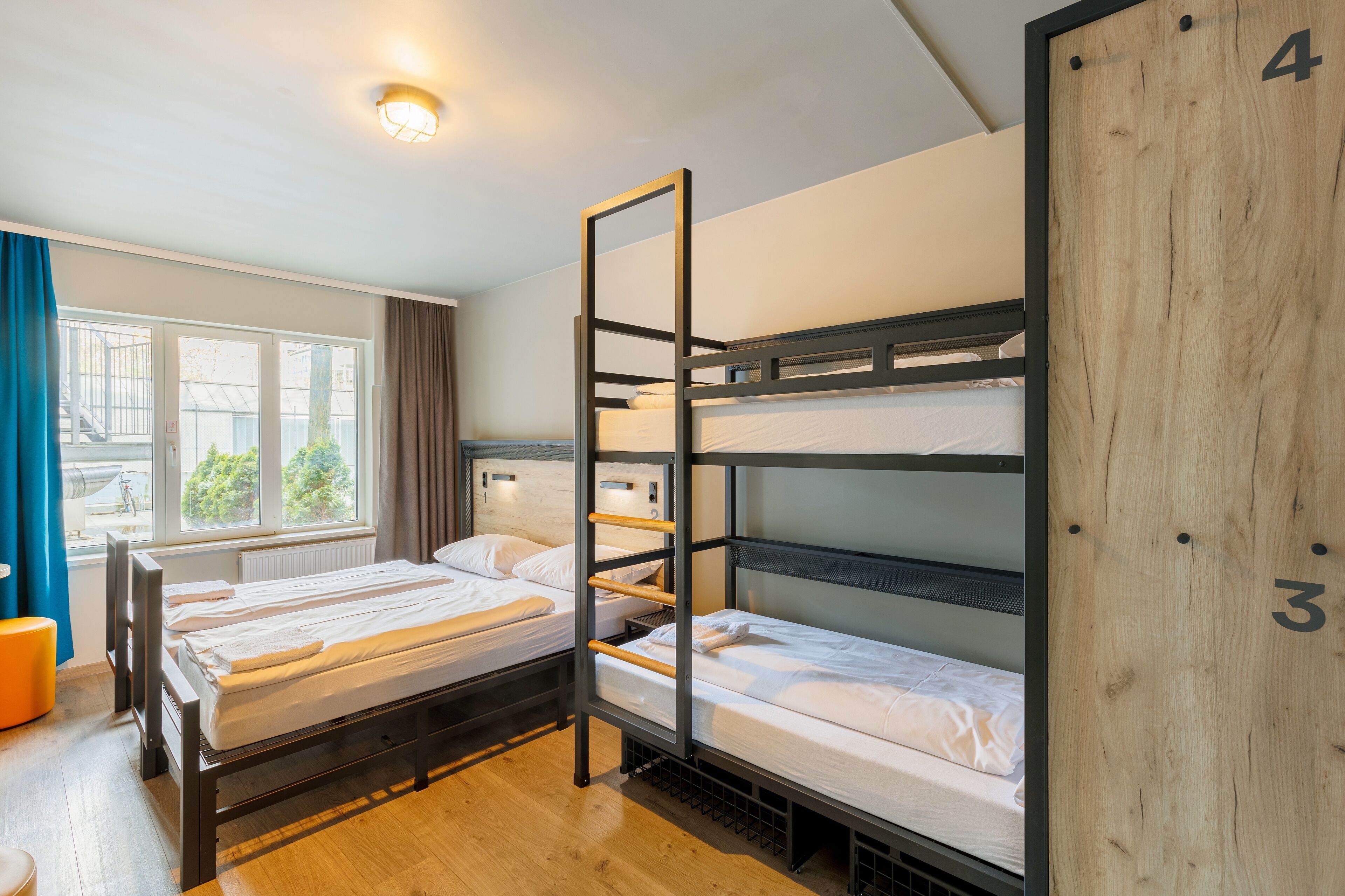 Un dormitorio con literas, una ventana con cortinas y una pared de madera con un número.