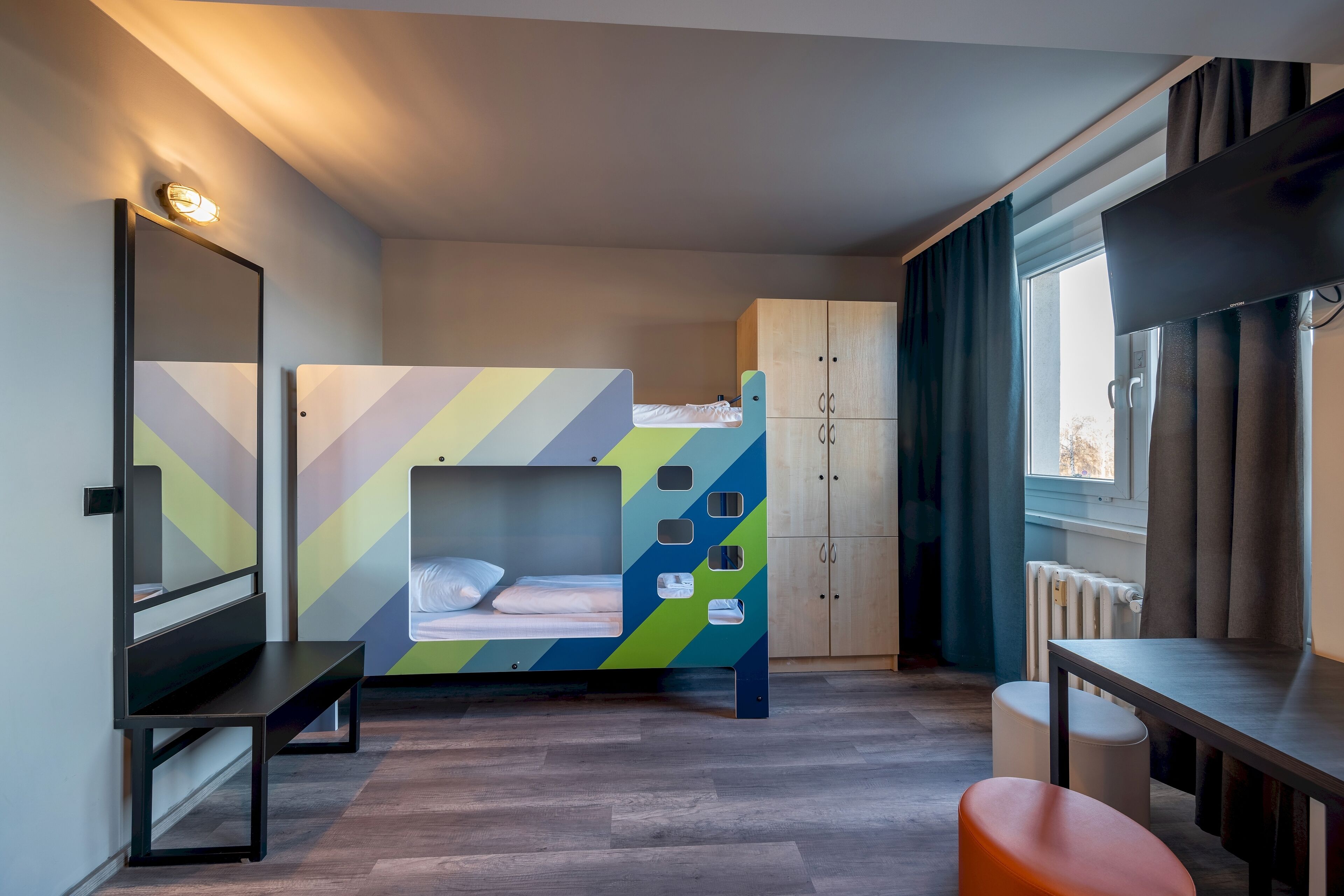 Une chambre avec un lit superposé, un bureau, une chaise, une armoire et une fenêtre avec des rideaux.