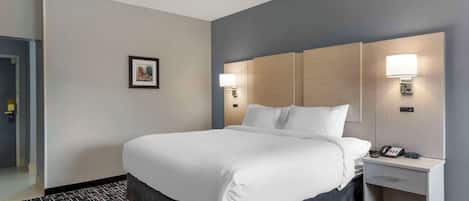 A hotel room with a large bed, bedside lamps, a nightstand with a phone, and a framed picture on the wall.