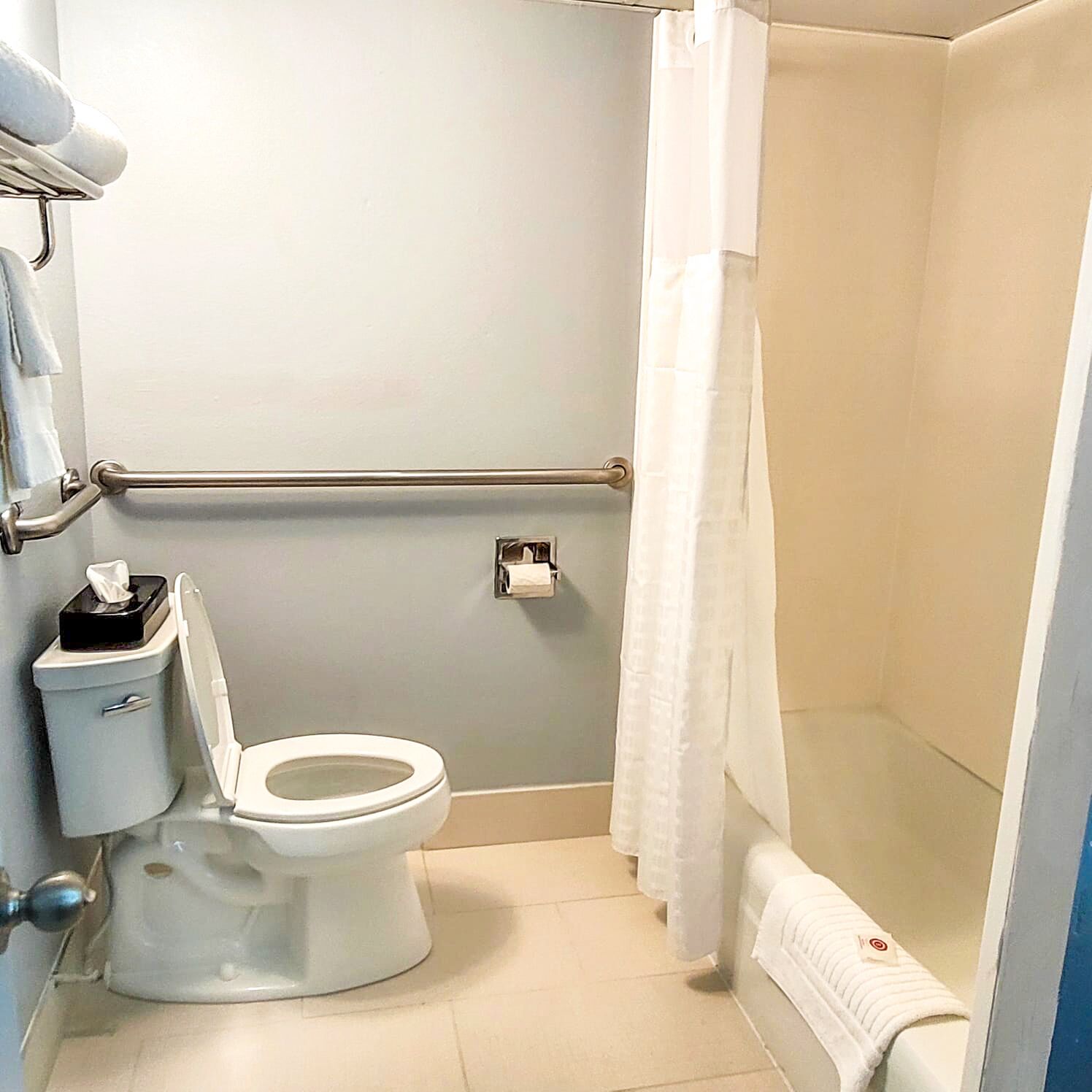 Un bany amb vàter, bidet, penjador de tovalloles i cortina de banyera.