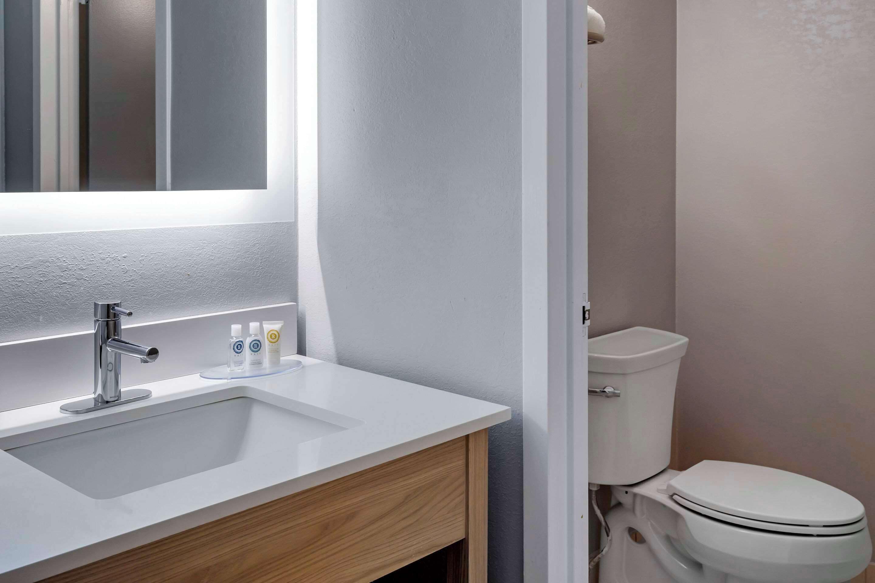 A modern bathroom with a white sink, chrome faucet, and a toilet.