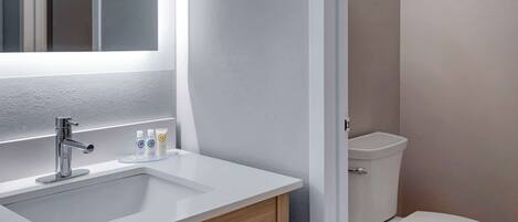 A modern bathroom with a white sink, chrome faucet, and a toilet.