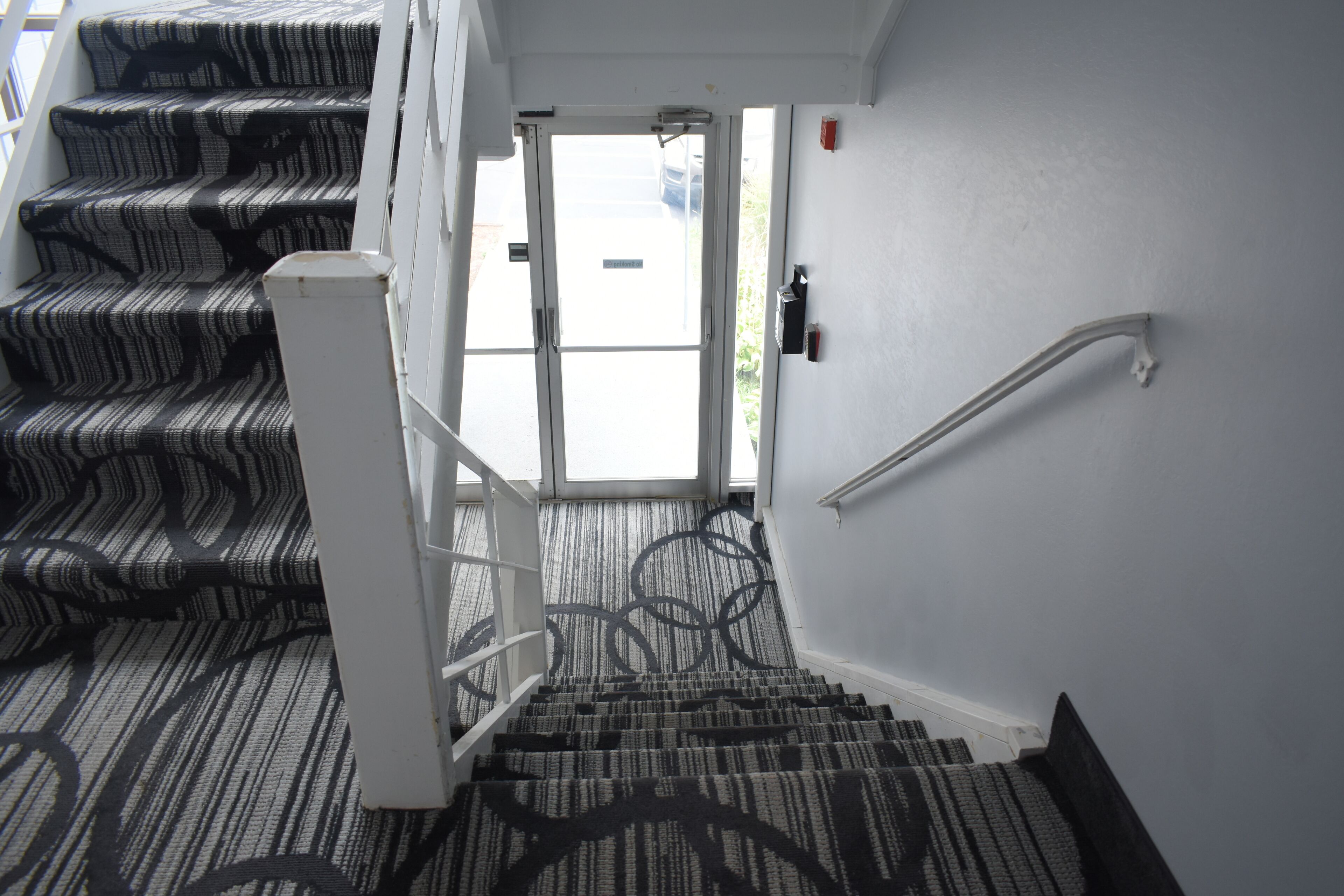 Eine Treppe mit gemustertem Teppich führt zu einer Tür.