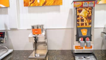 Un dispensador de jarabe con sistema de bombeo, una cafetera y un anuncio en la pared.