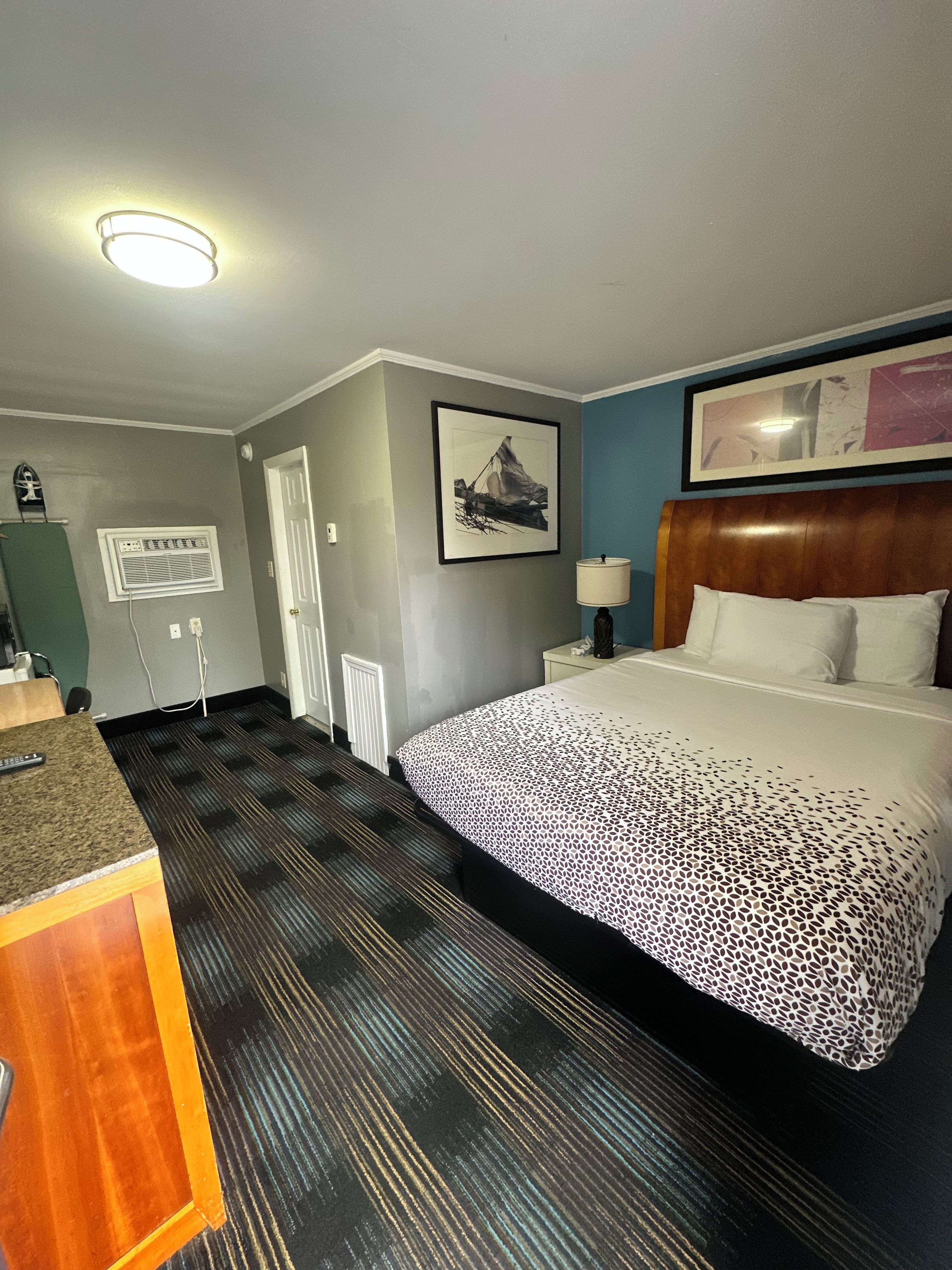 Ein Hotelzimmer mit einem Bett, einem Schreibtisch, einem Stuhl, einem Fenster und einer Tür.