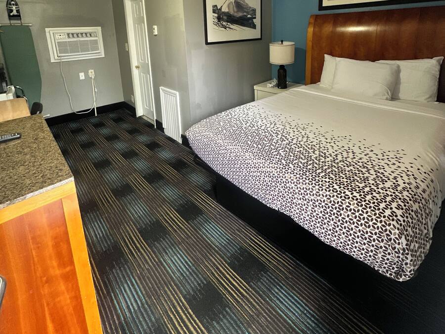 Ein Hotelzimmer mit einem Bett, einem Schreibtisch, einem Stuhl, einem Fenster und einer Tür.