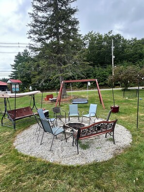 An outdoor seating area with a swing set, chairs, and a fire pit. - Pilgrim Inn & Cottages (Plymouth)