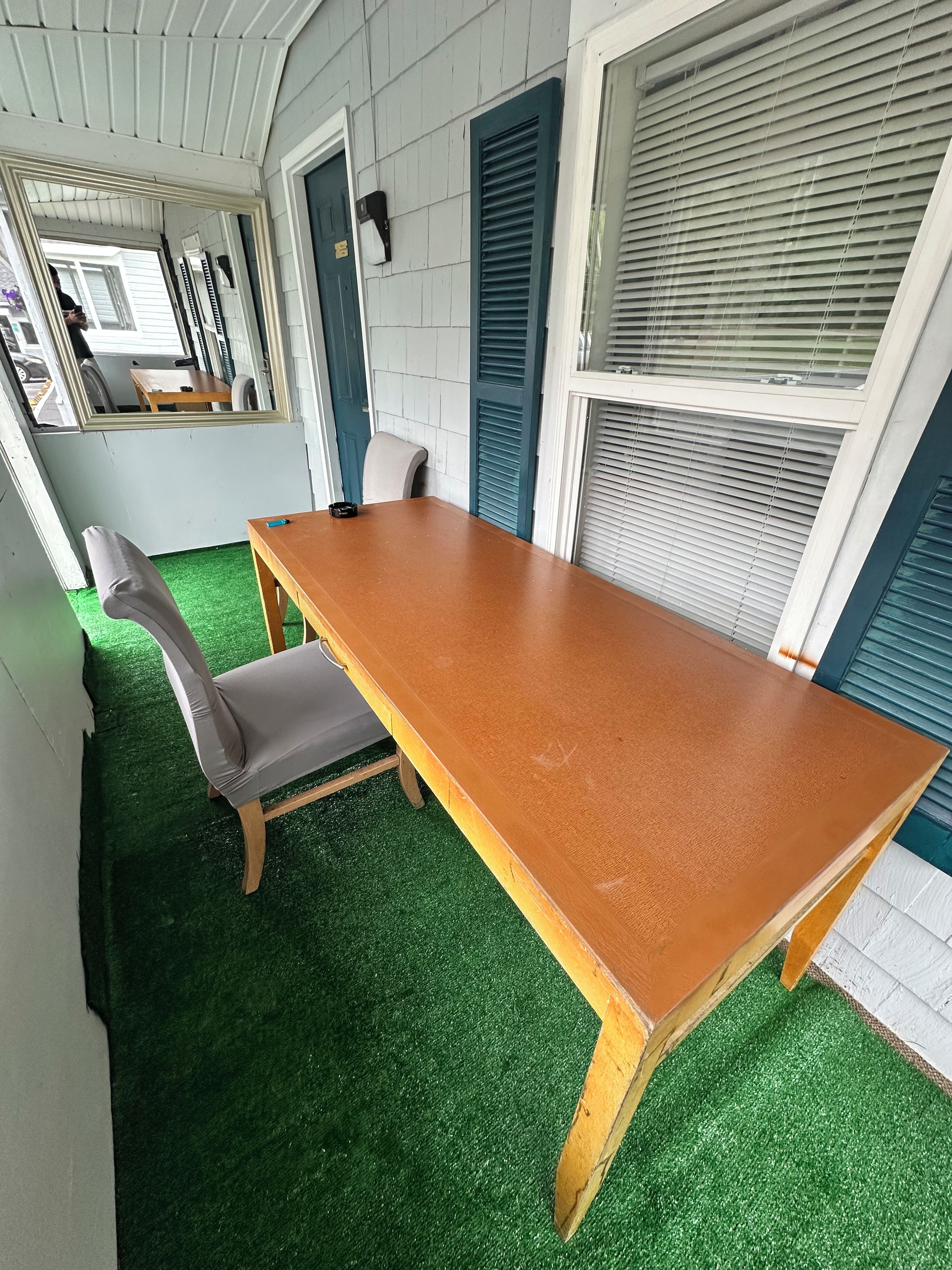 Ein Zimmer mit einem Holztisch, einem grauen Stuhl und einem Boden aus grünem Kunstgrün.