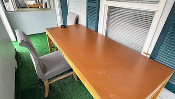 Ein Zimmer mit einem Holztisch, einem grauen Stuhl und einem Boden aus grünem Kunstgrün.