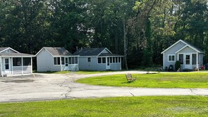 A row of small, single-story cabins with a grassy lawn in front. - Pilgrim Inn & Cottages (Plymouth)