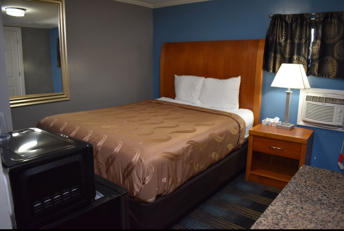 Une chambre d’hôtel équipée d’un lit, d’une table de chevet, d’une lampe, d’un climatiseur et d’un téléviseur.