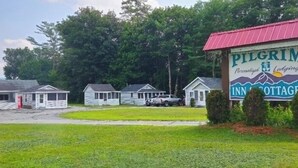 A motel with a sign reading "PILGRIM Personalizing Lodging INN COTTAGE" surrounded by small cabins. - Pilgrim Inn & Cottages (Plymouth)