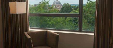 A hotel room with a large window, a chair, and a lamp.