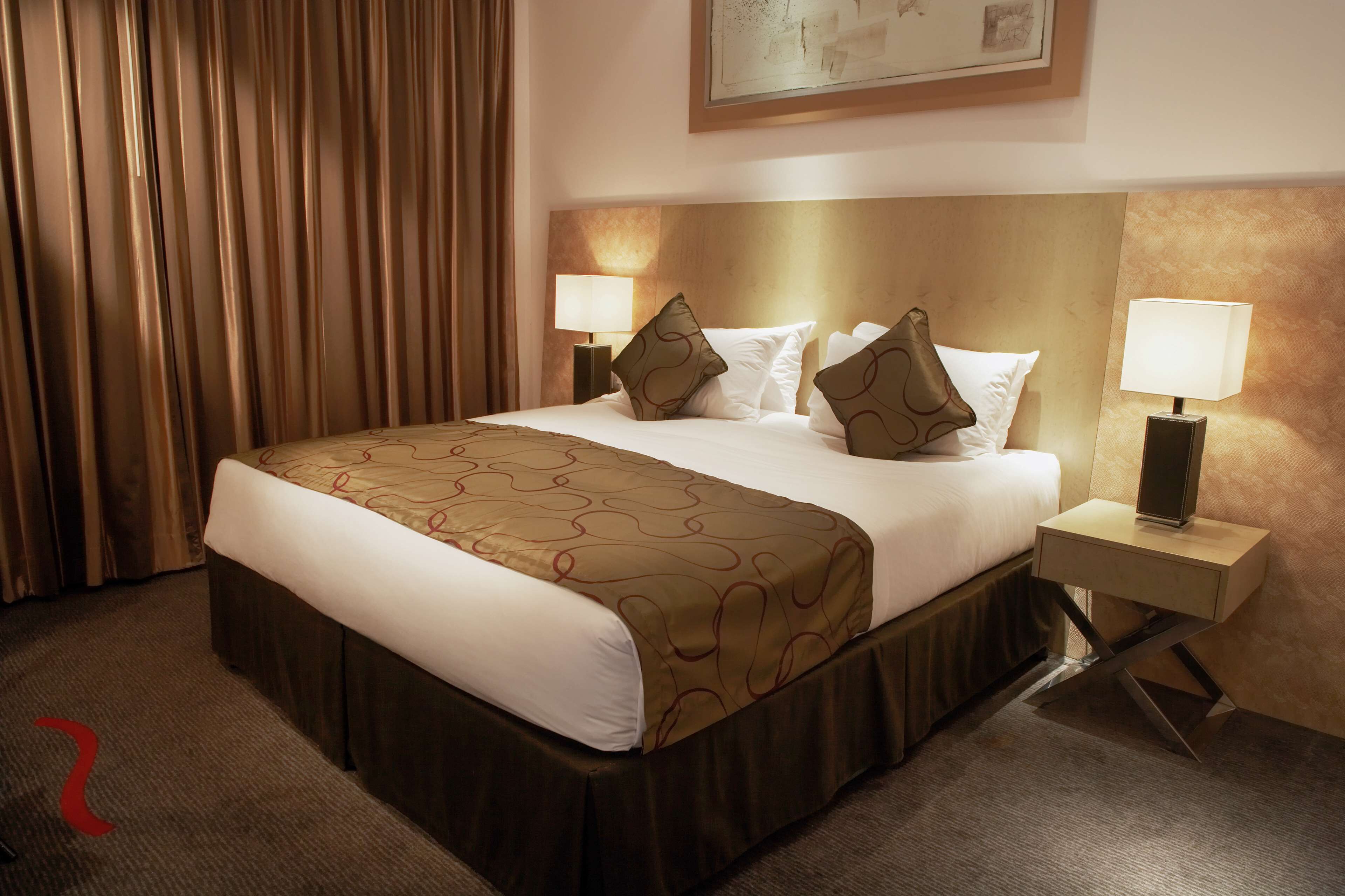 A hotel room with a large bed, two bedside tables, and a headboard.