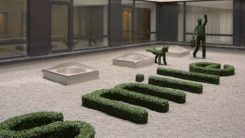 A spacious atrium with a modern design, featuring a central open area with geometric landscaping and a person walking.